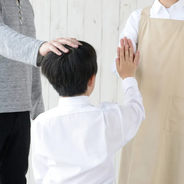 子どもの頭に優しく手を添える大人。親子整体や安心感を与えるタッチケアの様子